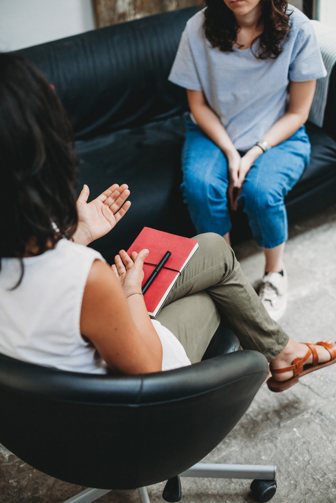 woman sitting on couch with therapist sitting across from her