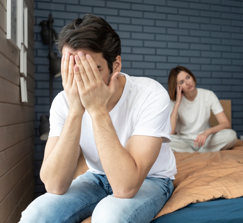 Frustrated and depressed man sitting on the edge of the bed after conflict with his wife because of his erectile dysfunction problem