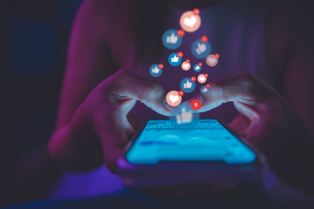 person on social media with like bubbles hovering over phone